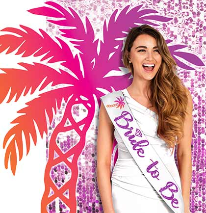 A woman wearing a white 'Bride to Be' sash with an ombre palm tree design in pink, orange, and gold shades.