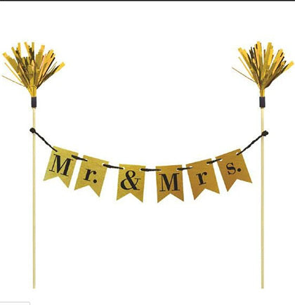Decorate the cake in style with this unique topper. The set includes two wooden picks with gold tinsel at the top and a banner that says Mr. &amp; Mrs. on gold metallic pennants. The perfect topper for the wedding rehearsal cake or wedding cake. 