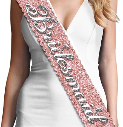 Have all your bridesmaid to match at the bachelorette party or bridal shower. Exclusively at The House of Bachelorette this rose gold sparkle sash says Bridesmaid in a pretty white flirty font. The sash is made with a sparkle fabric that does not shed and has a smooth satin on the backside for a pleasant fit.  